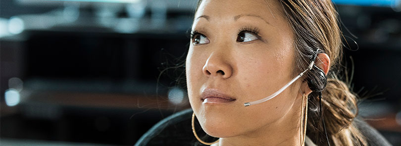 An emergency call taker with a headset on, at attention